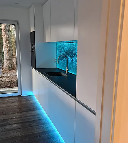 Küchenzeile mit weißem Schrankdesign, LED-Beleuchtung und Glasrückwand – individuelle Maßanfertigung