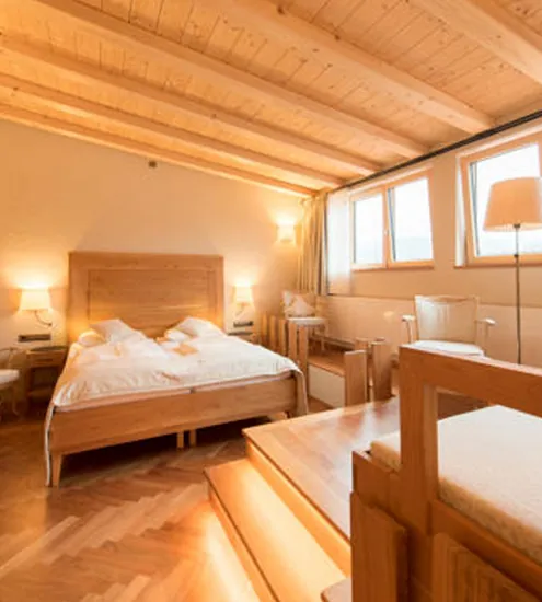 Hotelzimmer mit Doppelbett, Podest und Möbeln aus Holz – maßgefertigte Einrichtung vom Schreiner