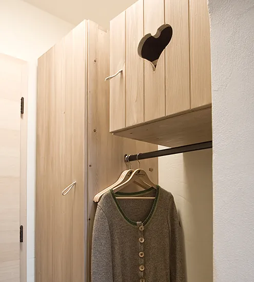 Garderobenschrank mit Herz-Ausschnitt aus Massivholz – individuelle Schreinerarbeit für Hotelausstattung