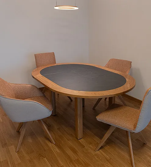 Runder Esstisch aus Massivholz mit eingelassener Schieferplatte und gepolsterten Stühlen – individuelles Tischdesign vom Schreiner.