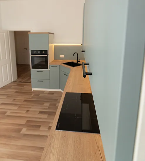 Moderne Küchenzeile in Pastellgrün mit Holzarbeitsplatte und schwarzen Griffen – individuelle Küche vom Schreiner.