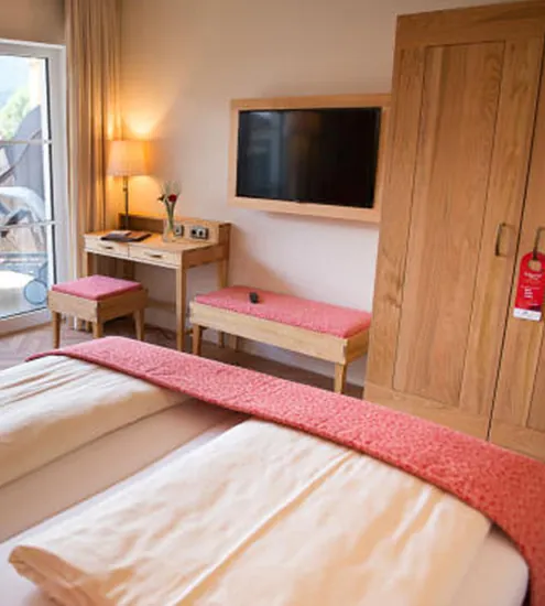 Hotelzimmer mit Doppelbett, Schrank und Fernseher – maßgeschneiderte Schreiner-Einrichtung in Holz
